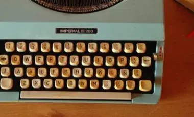 A typewriter and pen sit on a desk