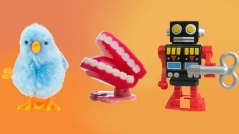 Three wind-up toys against an orange background