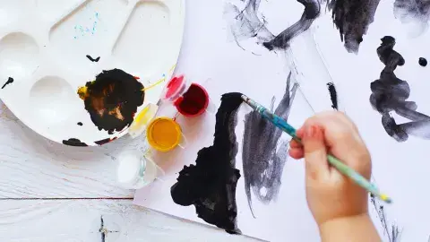 Child's hand holding paintbrush and painting
