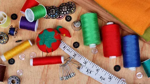 Image depicts thread, a ruler, pins, and other sewing materials